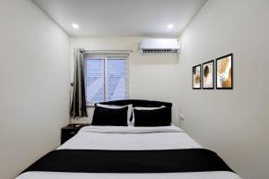 a bedroom with a black and white bed and a window at Hotel O Satyam Junction Seethammadhara in Visakhapatnam +30 photos