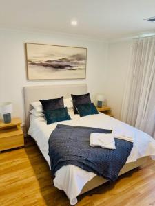 a bedroom with a bed with two blue pillows at Sittella's Vineyard Residence in Herne Hill