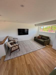 a living room with a couch and a television at Sittella's Vineyard Residence in Herne Hill