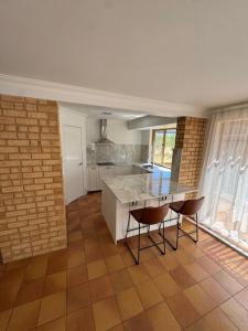 a kitchen with a counter and chairs in a room at Sittella's Vineyard Residence in Herne Hill