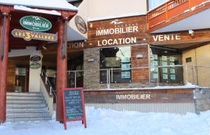 a restaurant with a sign in front of it in the snow at Lac Blanc Appartements VTI in Val Thorens