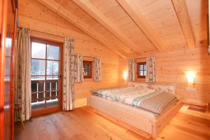um quarto num chalé de madeira com uma cama e uma janela em Chalet am Müllergut em Sankt Martin bei Lofer