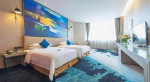 a hotel room with two beds and a large painting on the wall at MAIHAOHOTELS in Huangdong +75 photos