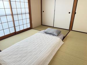 a bedroom with a bed in a room with windows at あかねや in Marugame