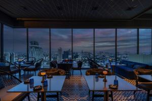 a restaurant with tables and chairs and a view of a city at INNSiDE by Meliá Bangkok Sukhumvit in Bangkok
