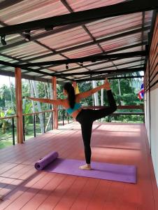 a woman doing a yoga pose on a yoga mat at Samui Land Haven in Taling Ngam Beach