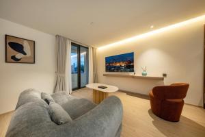 a living room with a gray couch and a chair at ROYS Hotel Bangkok in Bangkok