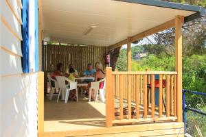 un porche con gente sentada en una mesa en Camping Roca Grossa, en Calella