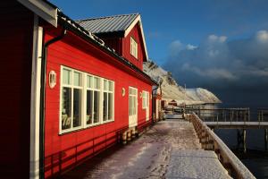 un edificio rojo en un muelle junto al agua en Sarnes Seaside Cabins, en Honningsvåg