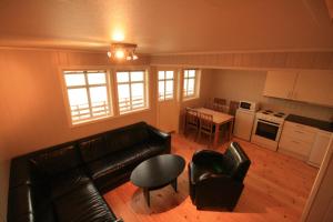 ein Wohnzimmer mit einem Sofa und einem Tisch sowie eine Küche in der Unterkunft Sarnes Seaside Cabins in Honningsvåg