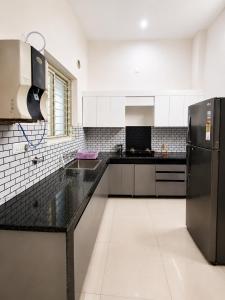 a kitchen with black counter tops and a refrigerator at Palam Villa in Kharar