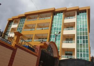 un edificio amarillo con balcones en un lateral en Résidence hôtelière La Roseline en Yaundé