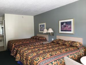 Dos camas en una habitación de hotel contigua en Riviera Motel, en Kissimmee