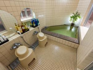 a bathroom with a bath tub with two toilets at Petit Resort Hotel Alcyon in Ito +70 photos