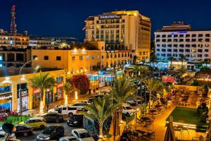 a city at night with cars parked in a parking lot at Pizza Street Hostel in Aqaba