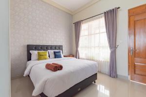a bedroom with a large bed and a window at Urbanview Syariah Hotel Kanigara Batu in Batu