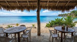 two tables and chairs on a beach with the ocean at Vista Oceanica in Ocho Rios