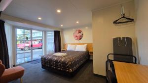 a hotel room with a bed and a sliding glass door at Admirals Motor Lodge in Blenheim