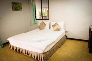 a bed with white sheets and pillows in a room at Rainbow House Resort in Kamphaeng Phet