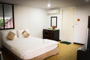 um quarto com uma grande cama branca e um espelho em Rainbow House Resort em Kamphaeng Phet