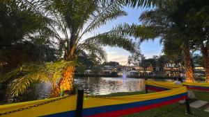 a view of a pond with a fence and palm trees at Hotel Casa Sharon in Cali