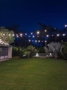a garden at night with lights in the background at The Saanj Villa in Sānand