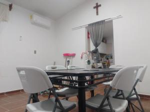 a dining room table with chairs and a cross on the wall at Oscar in Poza Rica de Hidalgo