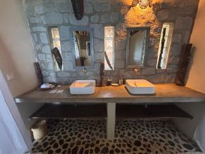 a bathroom with two sinks and a stone wall at Nosy Komba Lodge in Nosy Komba