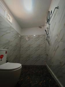 a bathroom with a toilet and a marble wall at Dambulla Tiger Rock Hotel with Mountain Viewpoint in Dambulla