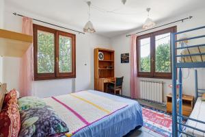 a bedroom with a bed and a desk and windows at La Pennica bnb in Pontremoli