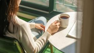 a woman sitting at a table with a cup of coffee at Daebudo Freesia Private Pool Villa in Ansan