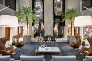 a lobby with chairs and tables and palm trees at Meliá Brasil 21 in Brasília