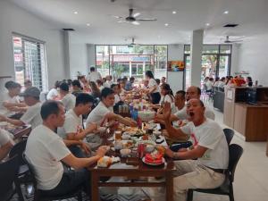 a group of people sitting at a table eating food at KHÁCH SẠN R Hotel in Sầm Sơn