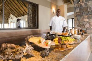 a man standing in a kitchen with a buffet of food at Safarihoek Lodge in Kamanjab +23 photos