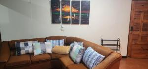 a brown couch with pillows on it in a room at Comfortable fully equipped apartment just 6 kilometers from Manuel Antonio, with parking and fast WiFi in Quepos