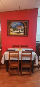a dining room with a red wall with a table and chairs at Comfortable fully equipped apartment just 6 kilometers from Manuel Antonio, with parking and fast WiFi in Quepos