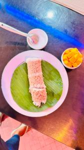 a plate of food with a piece of cake on a green leaf at Wonder Stay in Jaffna