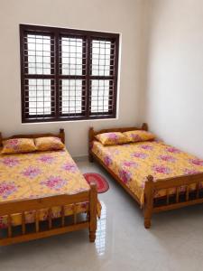 a bedroom with two beds and two windows at hill point stay in Kalasa