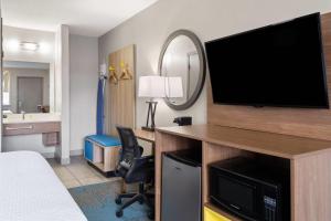 a hotel room with a bed and a desk with a television at Days Inn by Wyndham Ardmore in Ardmore
