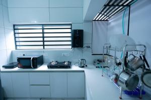a kitchen with white cabinets and a microwave at Nirmalyam Homestay in Kuttippuram