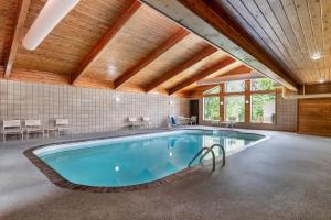 a large swimming pool in a room with a wooden ceiling at AmericInn by Wyndham Cloquet in Cloquet