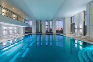 a large swimming pool with chairs in a building at JW Marriott Bucharest Grand Hotel in Bucharest
