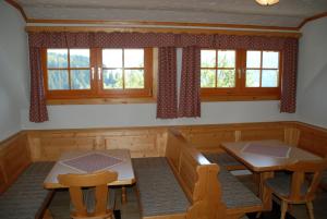 a dining room with two tables and chairs and windows at Ferienwohnung Lahnerhof in Arriach