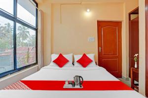 a bedroom with a bed with red pillows and a window at SPOT ON The New View Regency in Trivandrum
