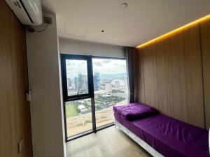 a room with a purple bed and a large window at Vue Aston in Phnom Penh