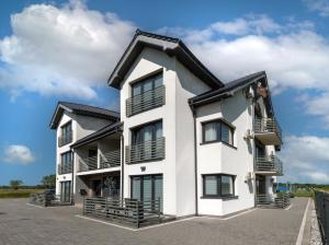 a white building with black windows and balconies at AWO Apartamenty in Łeba