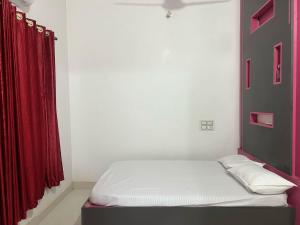 a bed in a room with a red curtain at Silent River Homestay in Perdūru