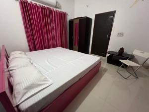 a bedroom with a bed with a red curtain and a chair at Silent River Homestay in Perdūru