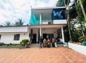 a group of people standing in front of a house at Silent River Homestay in Perdūru
