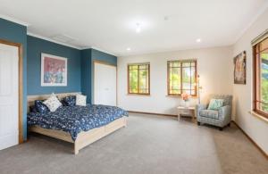 a bedroom with blue walls and a bed and a chair at Twilight Ridge in Bega